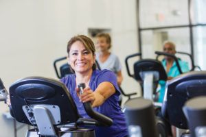 Mature Hispanic woman at the gym on exercise bike